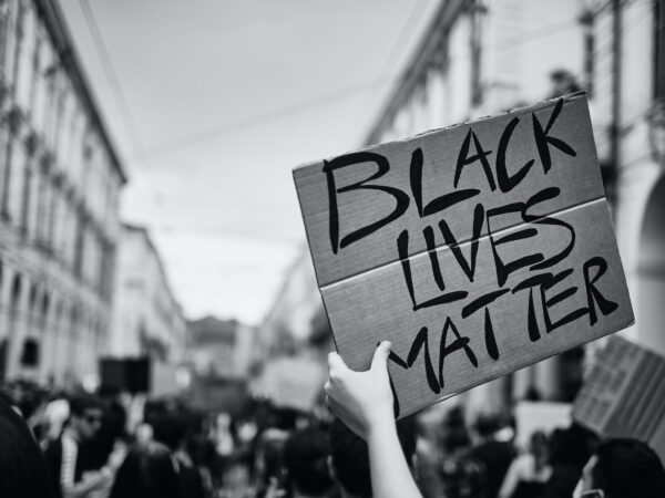grayscale photo of a person holding a placard with sign black lives matter